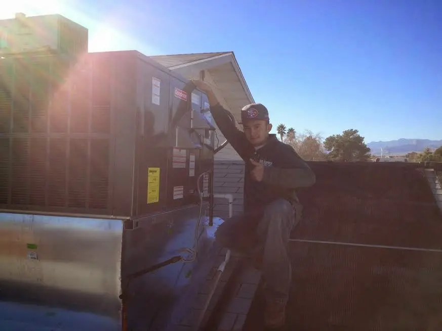 HVAC technician performing Boiler Repair on a rooftop unit in Harrison